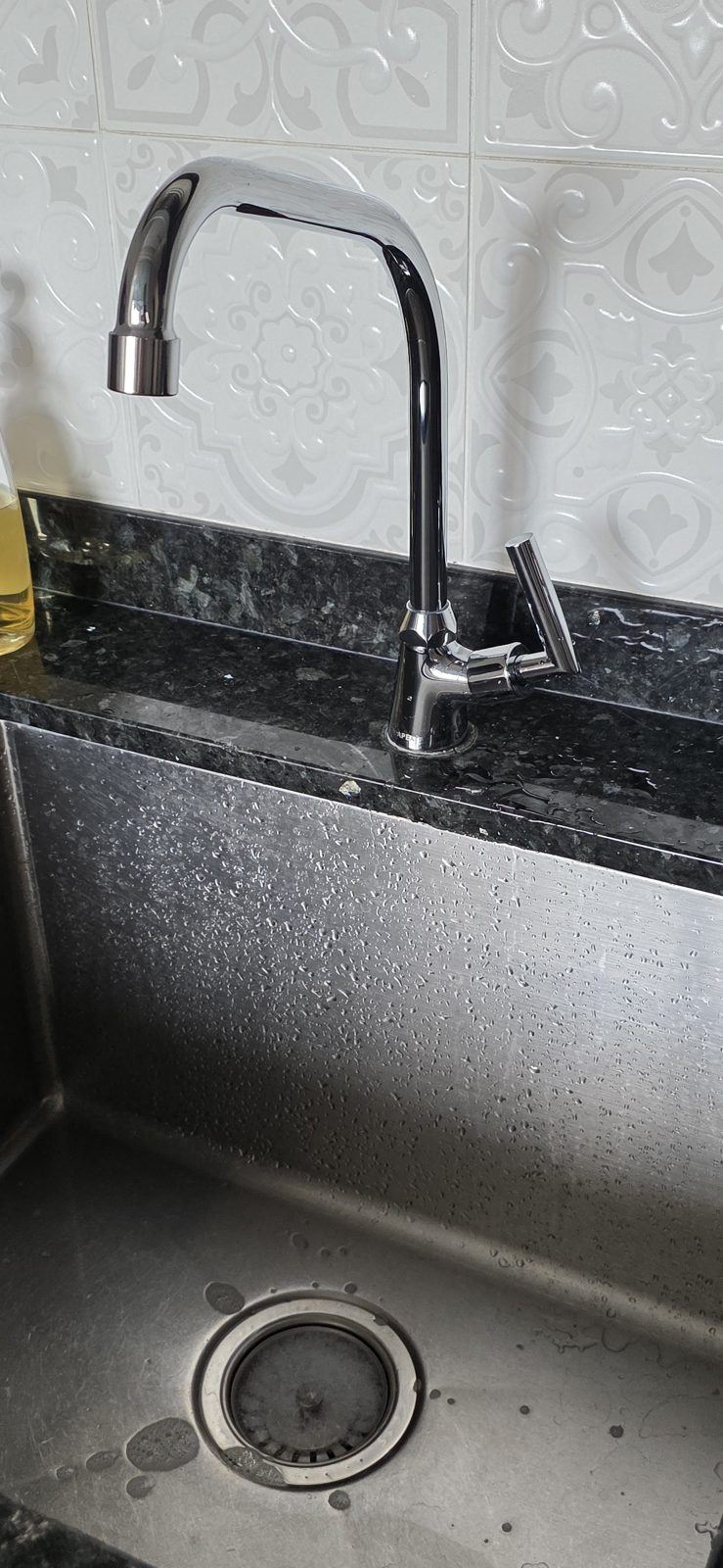 A new chrome gooseneck kitchen mixer on a black granite counter